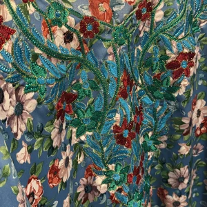 Blommig klänning med broderi - En färgglad klänning med blommigt mönster och detaljerat broderi i rött, grönt och blått. Klänningen har långa ärmar och en vacker design som fångar ögat.