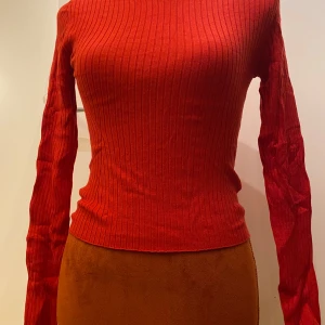 Röd ribbad tröja från H&M - Snygg röd ribbad tröja från H&M i en tight passform. Tröjan har långa ärmar och en rund halsringning, perfekt för att hålla stilen enkel och chic. Passar utmärkt till både jeans och kjol. Ribbstickad tröja  Längd: 47 cm Armhåla till armhåla: 35 cm  Inga bilder när den sitter på mig! Katter finns i hemmet