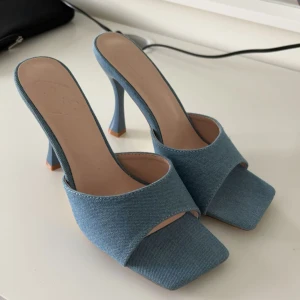 Blå jeansklackar - Snygga blå klackar i jeansmaterial med öppen tå och hög klack. Perfekta för en stilren look.