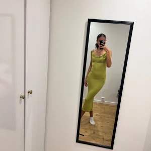 Grön klänning - Snygg grön klänning med draperad framsida och smal passform. Perfekt för en somrig look med sin eleganta design och mjuka material.