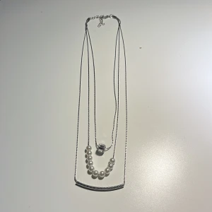 Halsband med pärlor och silverkedja - Elegant halsband med en tunn silverkedja och en rad vita pärlor. Halsbandet har en justerbar kedja för perfekt passform. Perfekt för att ge en stilren touch till din outfit.