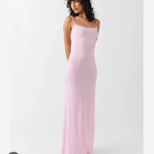 Rosa långklänning - Elegant rosa långklänning med smala axelband. Klänningen har en figurnära passform och är perfekt för somriga tillfällen. Den mjuka färgen och enkla designen ger en stilren look. Använd en gång så är som ny.