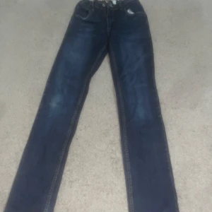 Levi's 510 Skinny Jeans - Snygga Levi's 510 skinny jeans i en klassisk mörkblå färg. Perfekta för en stilren look med en smal passform. Dessa jeans har den ikoniska Levi's-loggan och är tillverkade i slitstarkt denim. Storlek: 16 år (176cm) 16a. 