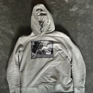 Grå hoodie från Limitato - Säljer en stilren grå hoodie från Limitato med en svartvit bild på framsidan. Tröjan har en klassisk huva och långa ärmar, perfekt för en avslappnad look.