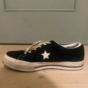 Svarta sneakers från Converse - Snygga svarta Converse sneakers i mocka med vit stjärndetalj på sidan. Skorna har klassisk snörning och en bekväm gummisula. Perfekta för en avslappnad stil.