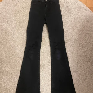 Svarta Peachy Flare jeans - Snygga svarta flare jeans från Peachy i storlek XS. De har en hög midja och en klassisk femficksdesign. Perfekta för en trendig look med sina utsvängda ben. Dom är använda 2-4 gånger 