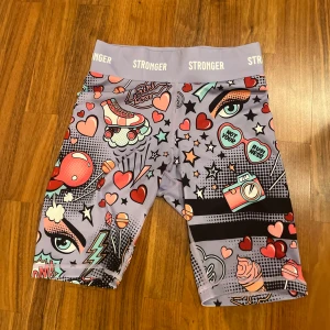 Färgglada träningsshorts från Stronger - Snygga och färgglada träningsshorts från Stronger med ett coolt pop art-mönster. Shortsen har en elastisk midja och är perfekta för att sticka ut på gymmet eller under löprundan.