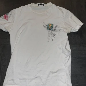 Vit t-shirt med tryck från Replay - Snygg vit t-shirt från Replay med unikt tryck. Använt ett fåtal gånger men inget synligt fel på tröjan. Nypris är 800 kr. Skriv för fler bilder. Tröjan är liten i storleken, jag har vanligtvis M i tröjor så denna passar även det.