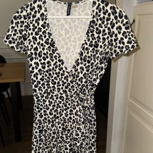 Leopardmönstrad omlottklänning från H&M -  leopardmönstrad omlottklänning från H&M med korta ärmar och knytband i midjan.