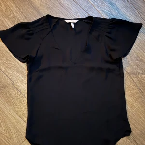 Svart blus med v-ringning -  svart blus med v-ringning och kort ärmad