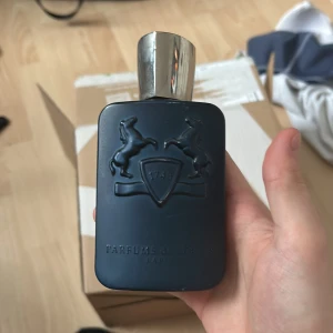 Tom parfymflaska från Parfums de Marly - Elegant mörkblå parfymflaska med silverfärgat lock från Parfums de Marly. Flaskan har en stilren design med två upphöjda hästar och en sköld med årtalet 1743.