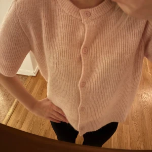 Rosa ribbad kofta - Säljer en söt rosa kofta med korta ärmar och knappar framtill. Den är ribbad och har en rund halsringning, perfekt för en avslappnad stil. Från Gina tricot, slutsåld.