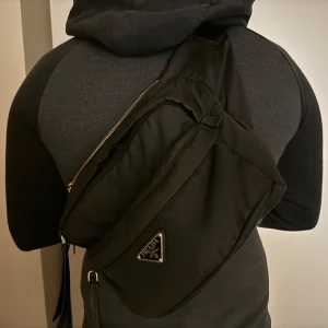 Äkta prada axelremsväska  - Äkta Prada Axelremväska, justerbart, 3 stora fickor och Prada loggan framtill. Använt den en semester och den är guld när man är ute. 