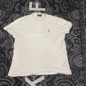Vit t-shirt från Polo Ralph Lauren - Snygg vit t-shirt från Polo Ralph Lauren med klassisk broderad logga i blått på bröstet. Perfekt för en stilren och avslappnad look. Säljer varan då den va lite för liten på mig. (Är lite större vid axlarna) så om du inte är det kommer den passa dig perfekt! Kan gå ner i pris vid snabb affär!