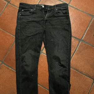 Svarta jeans från Calvin Klein - Snygga svarta jeans från Calvin Klein i modellen Slim Taper. De har en klassisk femficksdesign och en diskret logga på knappen. Perfekta för en stilren look.