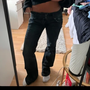 Svarta bootcut jeans - Snygga svarta bootcut jeans med låg midja och dubbla knappar fram. Perfekta för en avslappnad stil med en touch av retro. Passar bra till både sneakers och klackar.