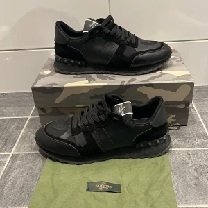 Valentino rockrunners - Snygga svarta sneakers från Valentino med en diskret camouflage-design. Skorna har snörning och en stilren look som passar perfekt för en trendig stil. Kvitto finns✅ tveka inte på att skicka frågor eller funderingar🤝