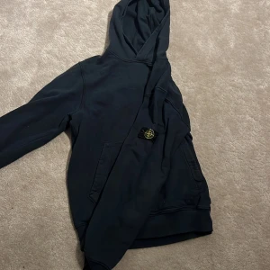 Blå Stone island hoddie - Hej, jag säljer nu min fina stone island hoddie eftersom den har blivit för liten den är köpt på Nk och det är Stone island junior. Scanan fungerar, 