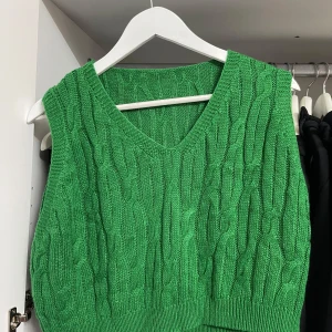 Grön stickad väst - Säljer en superfin grön stickad väst med ett snyggt kabelstickat mönster. Har en v-ringad design och är perfekt för lager-på-lager under hösten. Västen är i nyskick, passar perfekt för en trendig och bekväm stil. Från SHEIN, storlek L men passar M.
