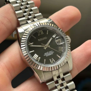 Seiko mod ”datejust” roman numerals 36mm - Hej! Snygg seikomod ”datejust”, så gott som ny utan några tecken på användning. Automatiskt Nh35 urverk. Pris går att diskuteras vid snabb affär. Medföljer extralänkar och mejsel.