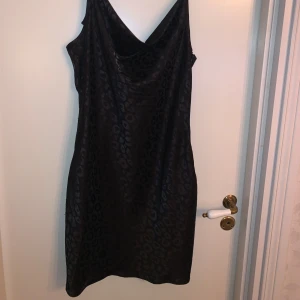 Svart leopardmönstrad klänning från Shein - Säljer en snygg svart klänning från Shein med leopardmönster. I glansigt satinliknande tyg