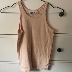 Beige/rosa linnetopp från Molo - Säljer en enkel och stilren beige/rosa linnetopp från Molo. Perfekt som ett basplagg i garderoben. Toppen är i bra skick och gjord av mjukt material som känns skönt mot huden. Passar perfekt till både jeans och shorts! Stretchigt material. Xxs-xs 😊💛