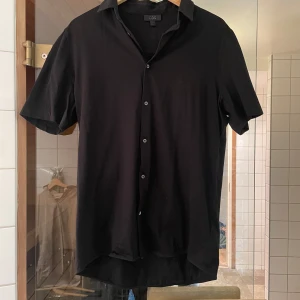 Svart kortärmad skjorta från Tiger of Sweden - Säljer en svart skjorta från cos. Skjortan är i gott skick, nästintill oanvänd.