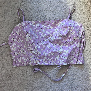 Lila blommig top - Crop top med öppen bak från zara. Kan skicka bild med den på om efterfrågas. Köpt men aldrig använd. Storlek S/XS