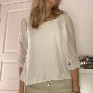 Vit blus med trekvartsärm - Säljer en stilren vit blus med trekvartsärm. Blusen har en luftig passform och är perfekt för både vardag och fest. Materialet är lätt och bekvämt 💕