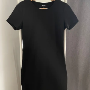 Svart klänning från Jennyfer - Säljer en stilren svart klänning från Jennyfer i storlek M. Klänningen har en klassisk design med korta ärmar och en figurnära passform som ger en elegant look. Perfekt för både vardag och festliga tillfällen!
