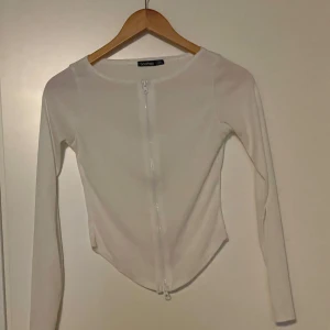 Boohoo - Säljer en stilren vit kofta från Zara. Den är ribbad och har en dragkedja framtill, vilket ger den en modern look. Perfekt för både vardag och fest! 💫