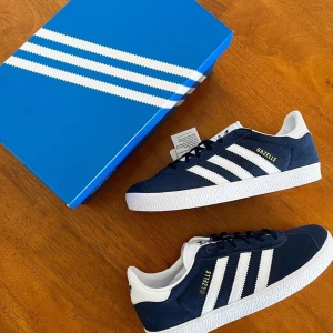 Adidas Gazelle i marinblått och vitt - Säljer ett par snygga Adidas Gazelle sneakers i marinblått med vita detaljer. Nyskick, och nypriset är ca 1200