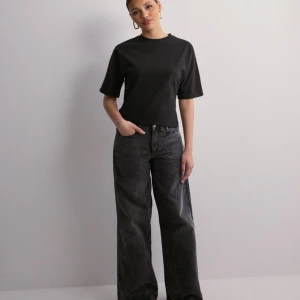 Svart topp med knyt i ryggen - Säljer en stilren svart topp med korta ärmar och en snygg knytning i ryggen. Toppen har en normal passform och är perfekt för både vardag och fest. Den är gjord i ett mjukt och bekvämt material som känns skönt mot huden.