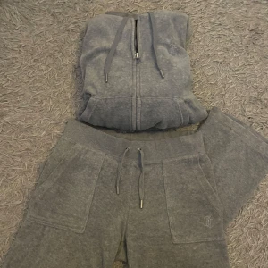 Grå Juicy Couture sett - Säljer mitt gråa sett från Juicy Couture i st xs, använd ett fåtalgpånger. Dock ramlade knappen på byxan av efter 3 användningen så det saknas en knapp. Annars är det i fint skick🥰