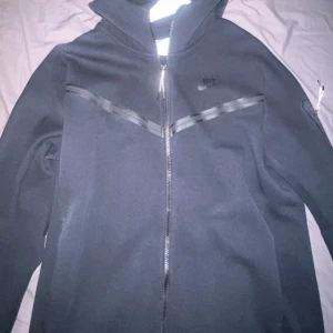 Nike Tech - Helt svart Nike tech i storlek M, kanske använt 1-3 gånger. Ser helt ny ut och helt äkta!