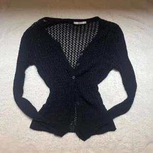 Mörkblå  kofta med knappar - Snygg mörkblå  kofta med knappar framtill. Den har ett genombrutet mönster och långa ärmar, perfekt för lager på lager-stil. Passar bra till både jeans och kjol. Storlek S