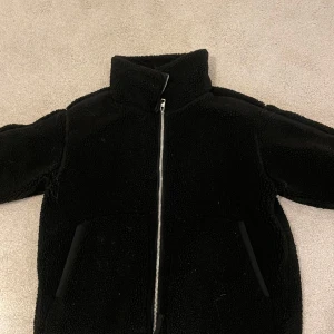 Svart teddyjacka från H&M - Säljer en svart skit populär och helt slutsåld teddyjacka från H&M med dragkedja framtill. Storlek S. Skriv för mer bilder eller frågor! 🩷 Använt fåtal gånger, finns tecken på användning!  Så som små fläckar på insidan, tror dock detta kan gå bort vid en tvätt!, men skriv för bilder. Kan sänka pris vid snabb affär så tveka inte på att förhandla! 