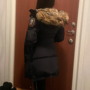 Svart parajumper long bear med pälsdetaljer - Snygg svart parajumpers jacka med stor huva och pälsdetaljer. Den är lång och perfekt för en kall vinterdag. Vanligtvist har jag Xs i storlek men S passar bra. Pälsen är äkta. Kan gå ner i pris vid snabb affär,skriv till mig innan du köper💞