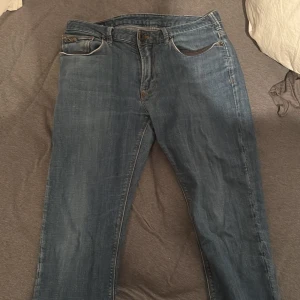 Blå jeans från Emporio Armani - Snygga blå jeans från Emporio Armani med klassisk femficksdesign och subtila logodetaljer. Jeansen har en normal passform och är tillverkade i slitstarkt denim. Perfekta för en stilren look.