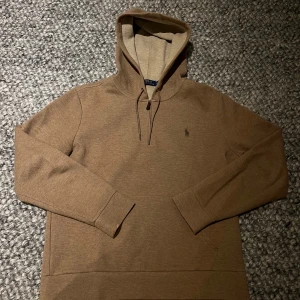 Brun hoodie från Polo Ralph Lauren - Säljer en stilren ljus brun hoodie från Polo Ralph Lauren. Den har en klassisk design med dragsko i huvan och en liten broderad logga på bröstet. Sällan använd, skick 10/10