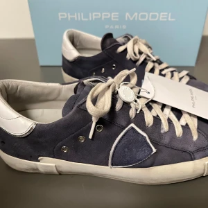 Philippe Model sneakers i blå mocka - Kom med bud! Snygga Philippe Model skor i blå mocka. Dom är i storlek 40 och perfekt om man vill ha ett par bra skor till sin outfit. Köpta som nya. Kartong och extra originalsnören medföljer. 
