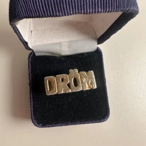 Maria Nilsdotter ring ”DRÖM” - Såå fin ring från Maria Nilsdotter. Pläteringen har skafts bort lite och lite repig men ingenting man tänker på när man har den på sig. Tror den är storlek 18