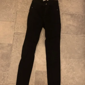 Svarta jeans från gina  - Snygga svarta jeans från gina, modell Molly. De har en tight passform och är perfekta för en stilren look. Klassisk design med knapp och dragkedja framtill.