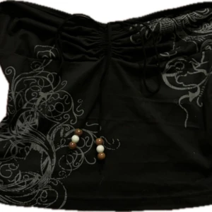 Svart offshoulder topp med mönster - Snygg svart offshoulder topp med dekorativa snören och pärlor framtill. Toppen har ett unikt mönster i grått och vita detaljer som ger en cool look. Perfekt för att sticka ut i mängden!