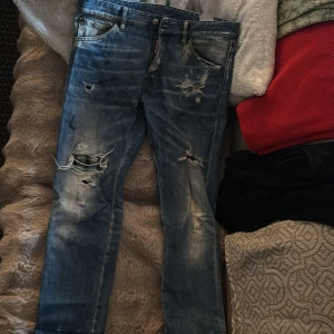 Blå jeans från Dsquared2 - Snygga blå jeans från Dsquared2 med slitna detaljer och en cool, distressed look. De har en klassisk femficksdesign och knappgylf. Perfekta för en avslappnad stil med en touch av edge.