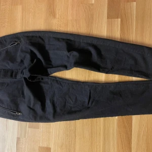 Mörkblåa byxor från Just Junkies - Snygga mörkblåa byxor från Just Junkies med dragkedjor vid fickorna. Perfekta för en stilren look. Byxorna har en bekväm passform och är tillverkade i ett mjukt material.