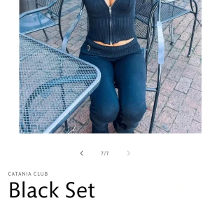 Svart ribbad set från Catania Club - Snyggt svart set från Catania Club med en ribbad design. Toppen har en dragkedja framtill och långa ärmar. Byxorna är matchande och har en bred linning. Perfekt för en stilren look. Strl S. Helt ny och oanvänd. Nypris 1500kr säljer för 400kr