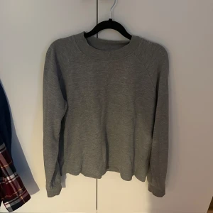 Grå Samsœ Samsœ Tröja - Säljer en stilren grå stickad tröja med rund halsringning. Tröjan har långa ärmar och en mjuk, bekväm passform. Lite kort i passformen men det är snyggt!