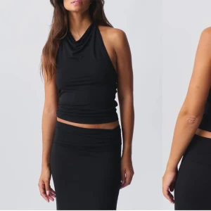 Svart halterneck topp - Snygg svart halterneck topp med en elegant draperad design. Toppen är ärmlös och har en åtsittande passform som framhäver figuren. Perfekt för en stilren look.