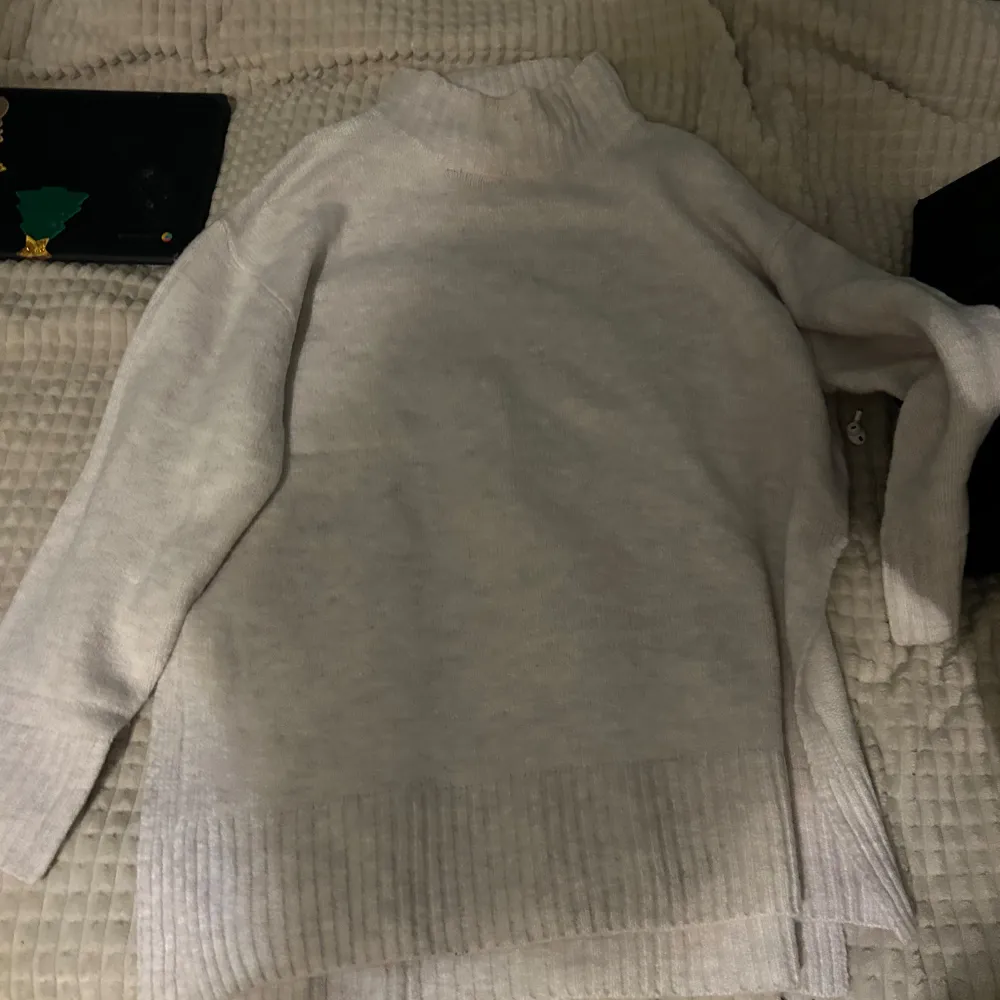 Säljer en mysig vit stickad polotröja med långa ärmar. Perfekt för kyliga dagar med sin höga krage och ribbade detaljer vid ärmslut och nederkant. En stilren och bekväm tröja för alla tillfällen.. Neuletakit & Villapaidat.